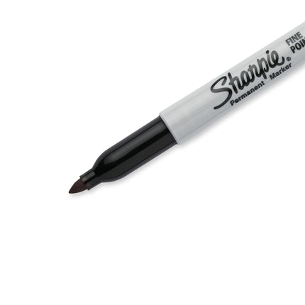 Cuatro marcadores Sharpie negros de punta fina con barril gris y tapas negras, alineados sobre fondo blanco.

